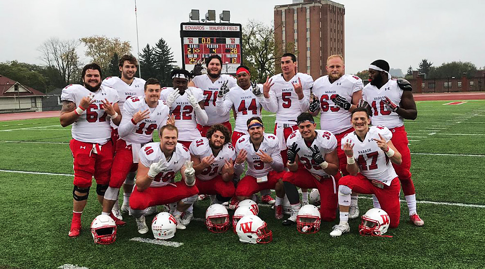 Wabash seniors flash Evan Hansen's No. 32 after the team's win at Wittenberg, with the scoreboard in the background. (Instagram photo, Kyle McAtee)
